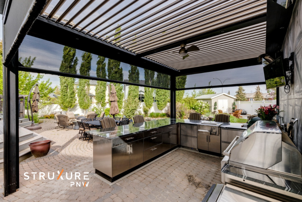 StruXure louvered pergola with adjustable aluminum louvers and MagnaTrack retractable screen system shown in a screened outdoor kitchen with ceiling fan and backyard view