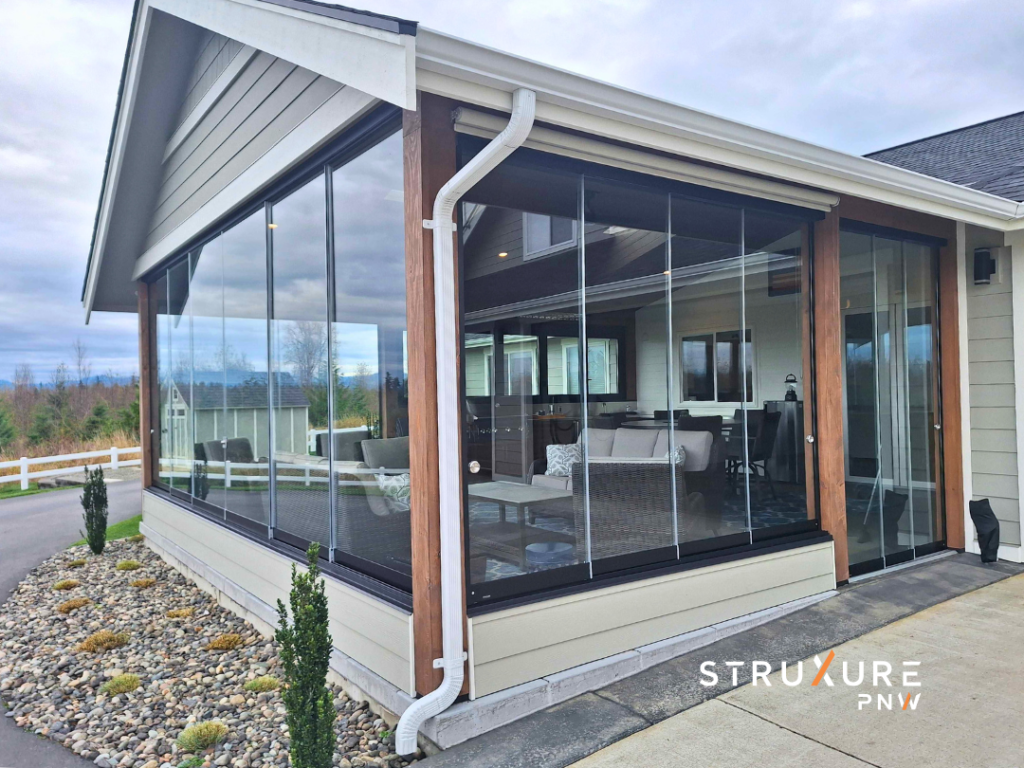 Porch enclosed with operable glass partitions that can seal off the space during cold months or open up entirely showing glass panels folded open to create an open air screened porch like feel