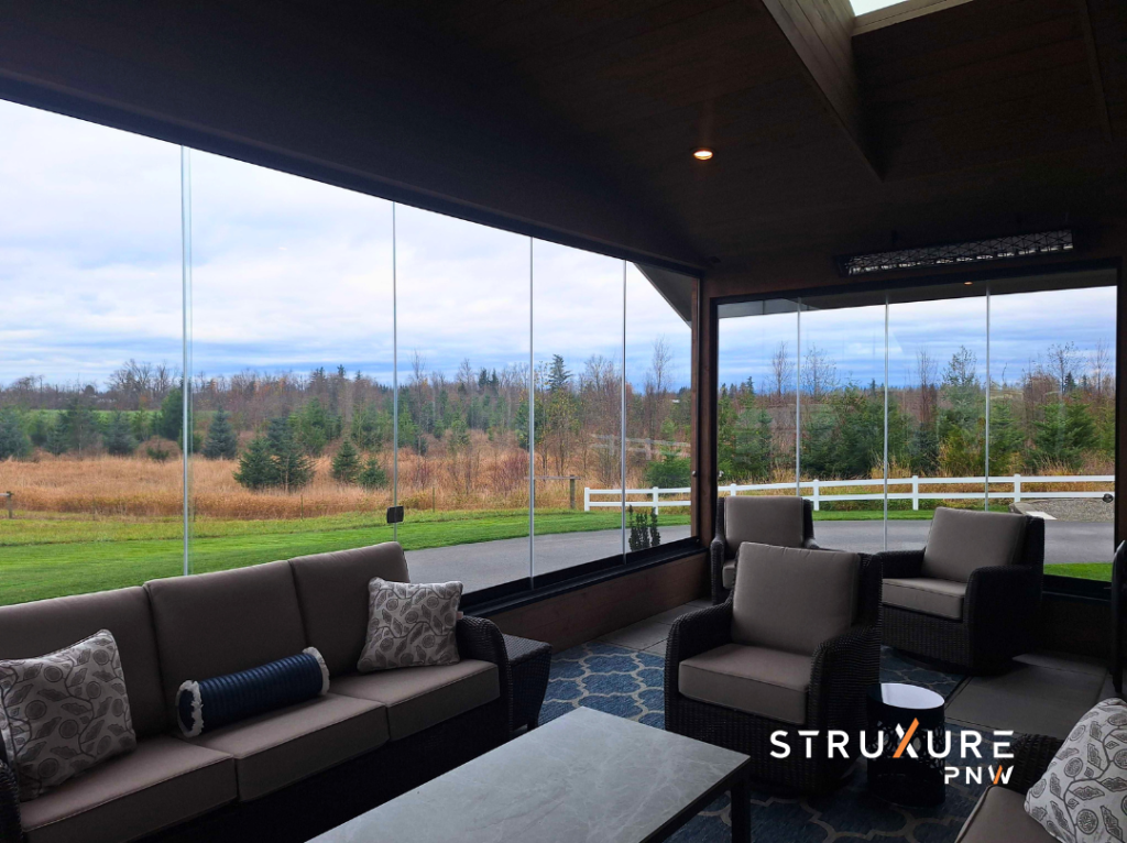 Inside looking out view from a porch enclosed with operable glass partitions showing a clear unobstructed view of the backyard through the glass with the panels in closed position