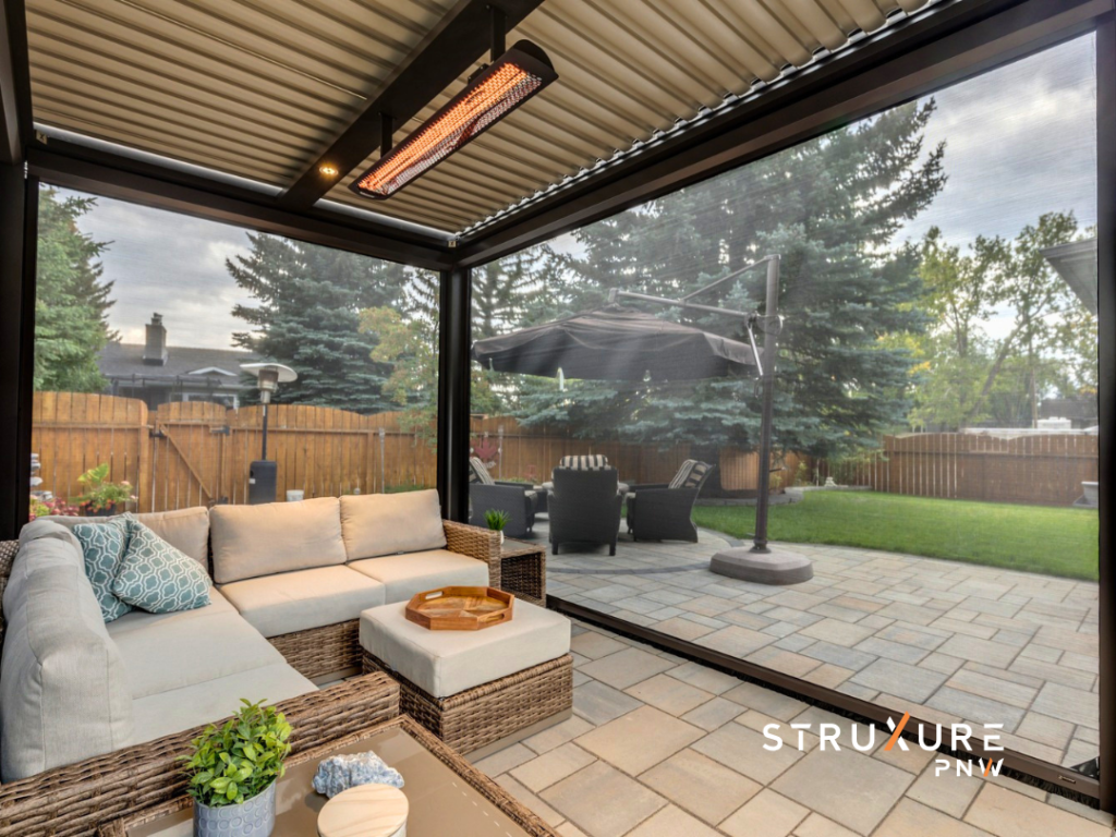 Patio enclosed with StruXure MagnaTrack screens and topped with a louvered pergola featuring a ceiling mounted infrared heater and a white outdoor sectional sofa inside the space