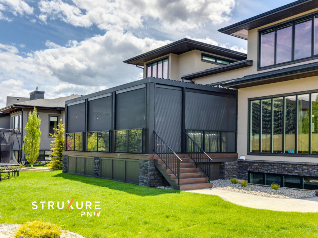 Luxury home viewed from the front yard with a screened in porch featuring screens lowered to the top of a half wall of glass on a sunny day with white fluffy clouds in a blue sky
